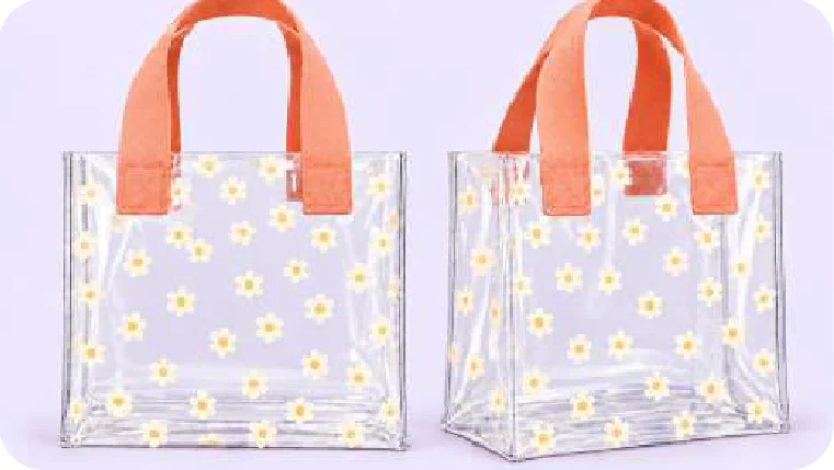 Dos bolsas transparentes con flores blancas de centro amarillo y manijas anchas naranja, de frente y en perspectiva